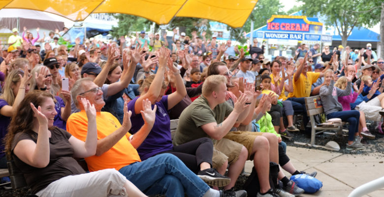 Crowd raising their hands and smiling at Baldwin Family Park