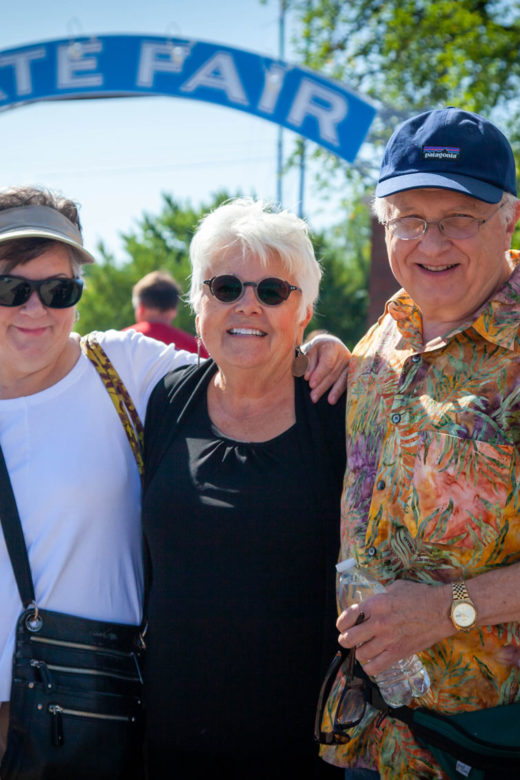 Three friends posing for a photo under the State Fair streetcar arch