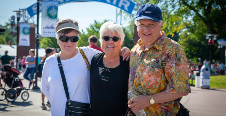 Three friends posing for a photo under the State Fair streetcar arch