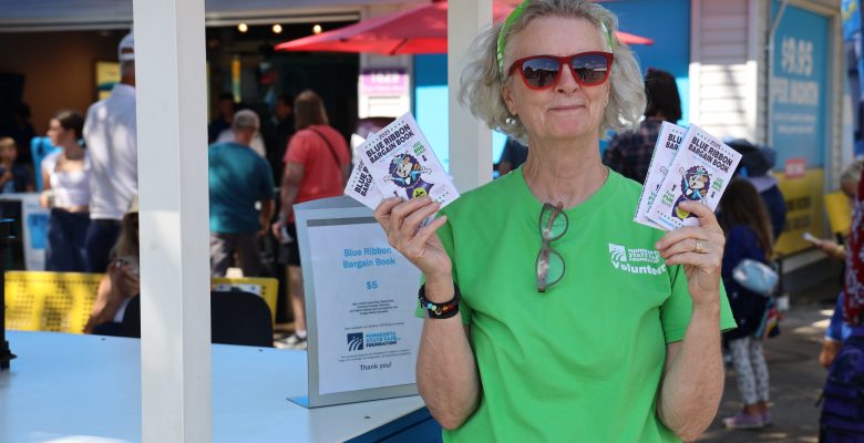 Foundation volunteer in front of a Blue Ribbon Bargain Book Cart